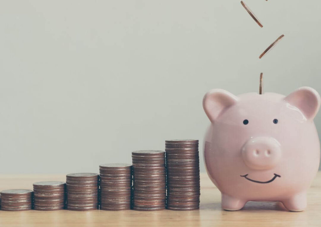 Strategies For Managing Your Money During Times Of Financial Uncertainty pennies stacking higher and higher next to piggy bank